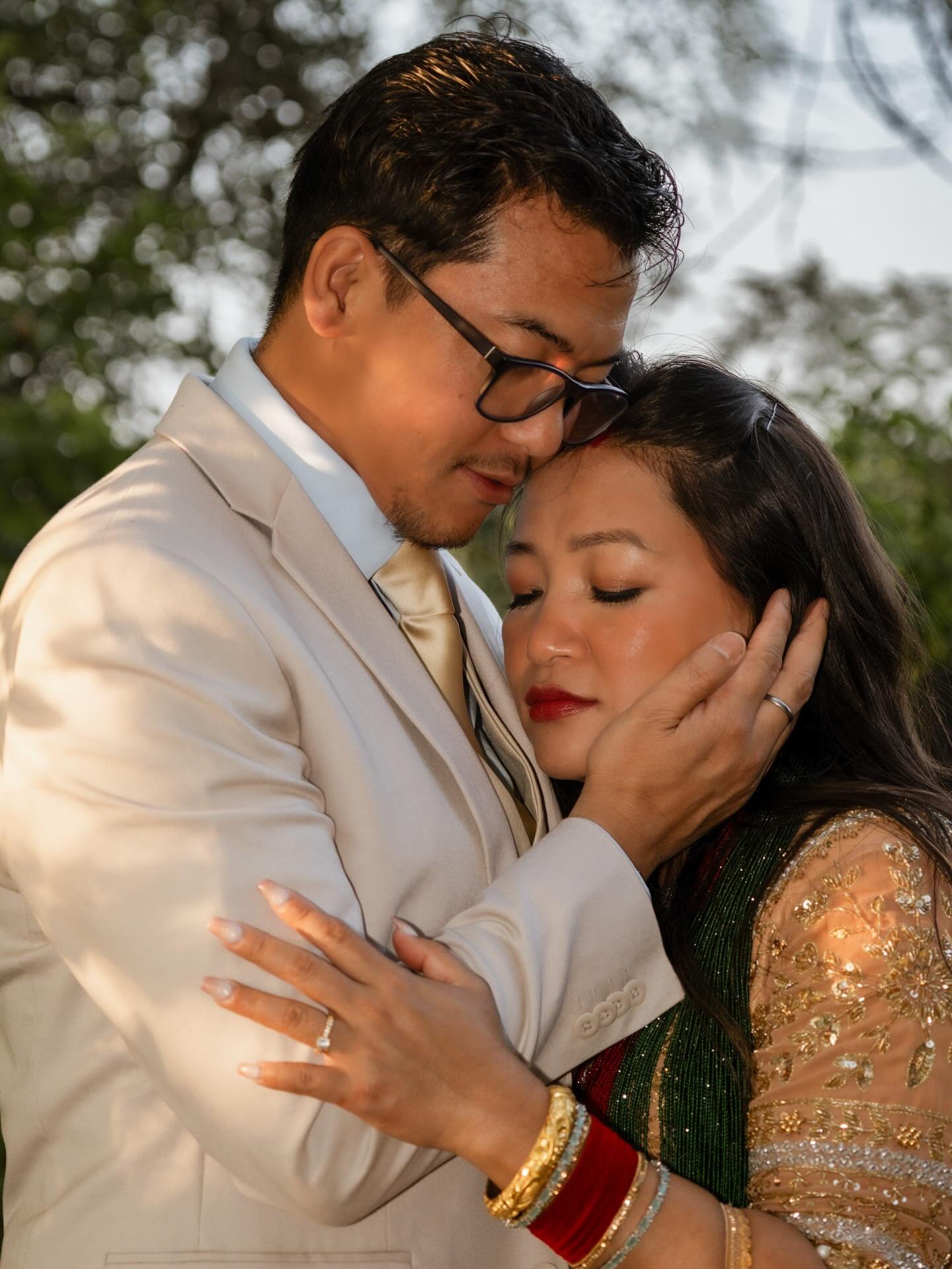 A man in a cream suit resting his forehead against a woman's as she holds his arm