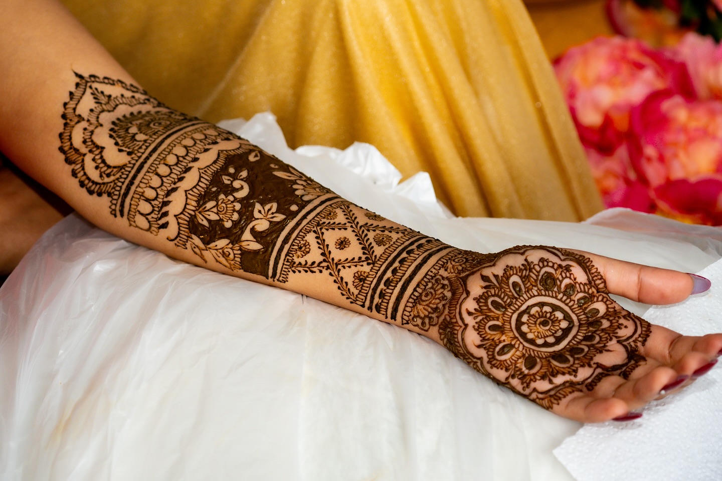 An arm and open palm covered in freshly applied, intricate mehendi