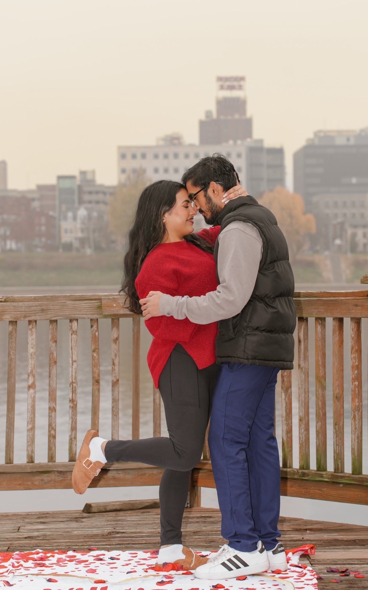 A couple kissing on a wooden deck on a foggy morning, she lifts one foot behind her